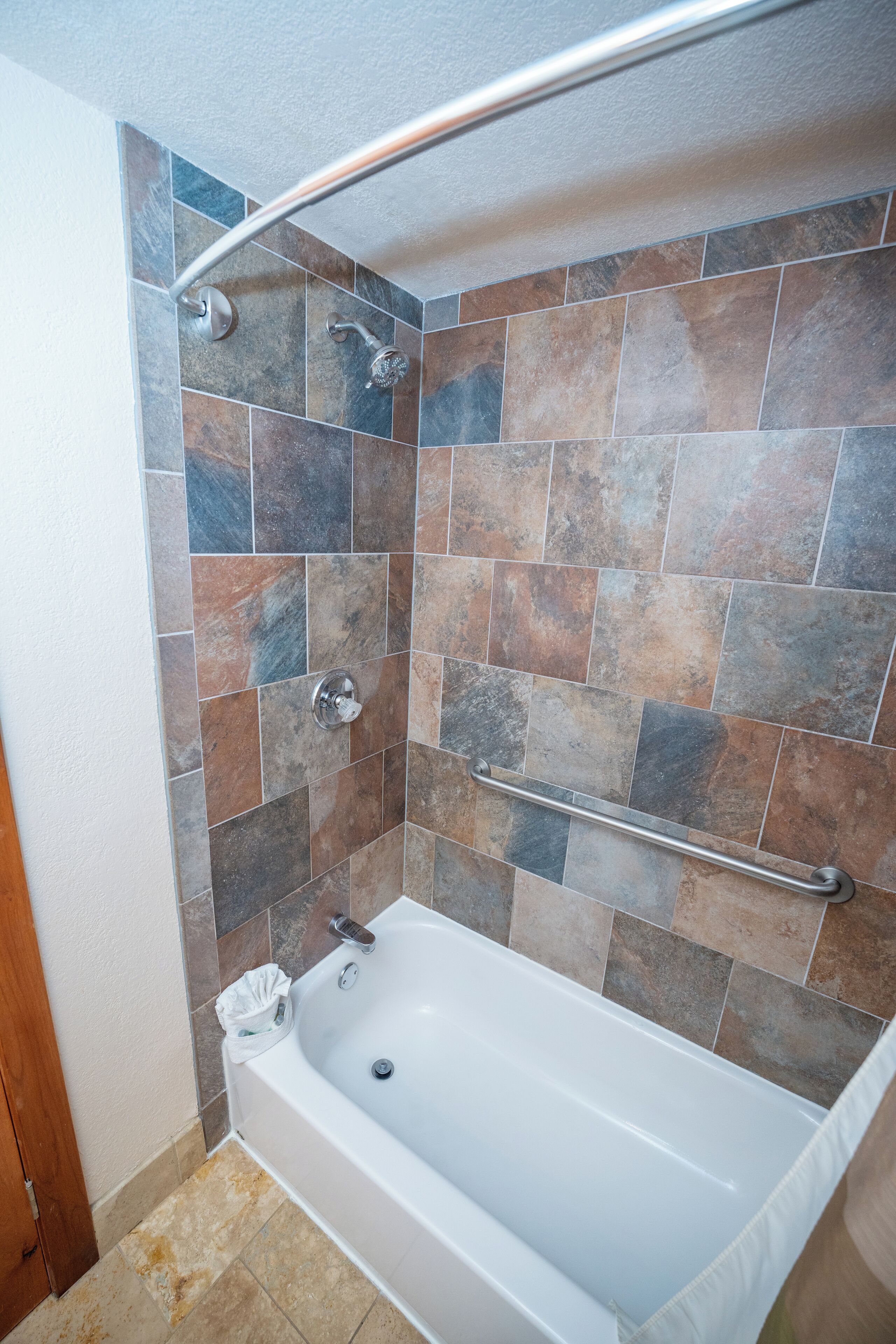 Une salle de bain avec une baignoire, une douche et des murs carrelés.