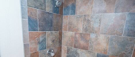 Un baño con bañera, ducha y paredes de azulejos.