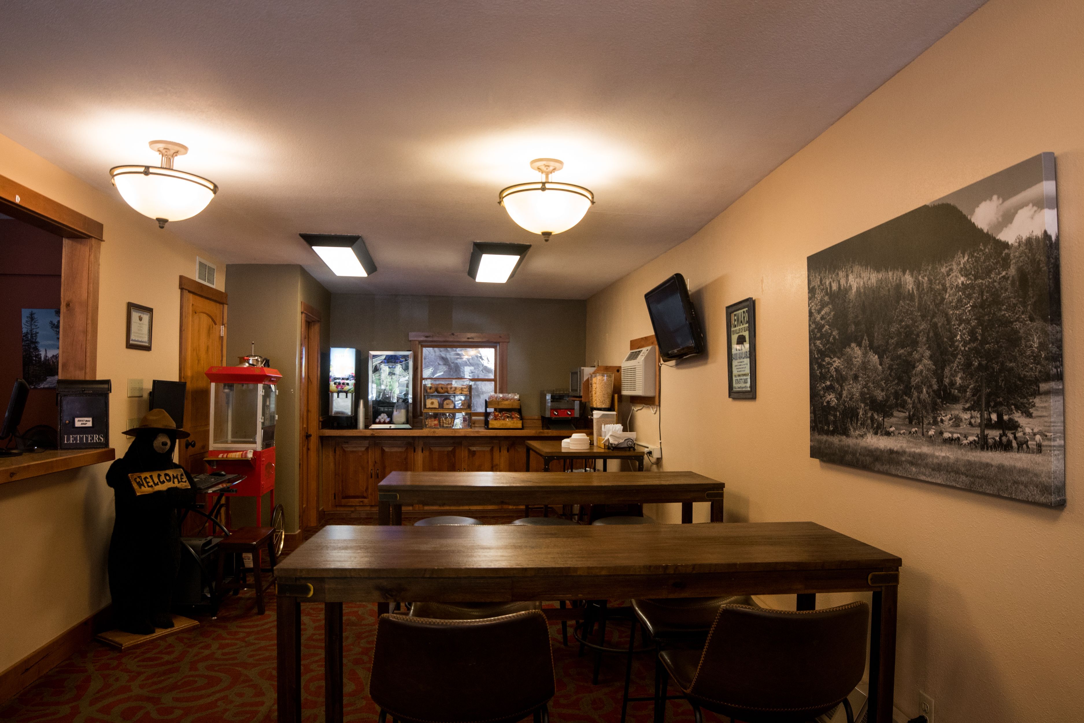 Un comedor con una mesa y sillas de madera, una zona de bar con un jukebox y un televisor montado.