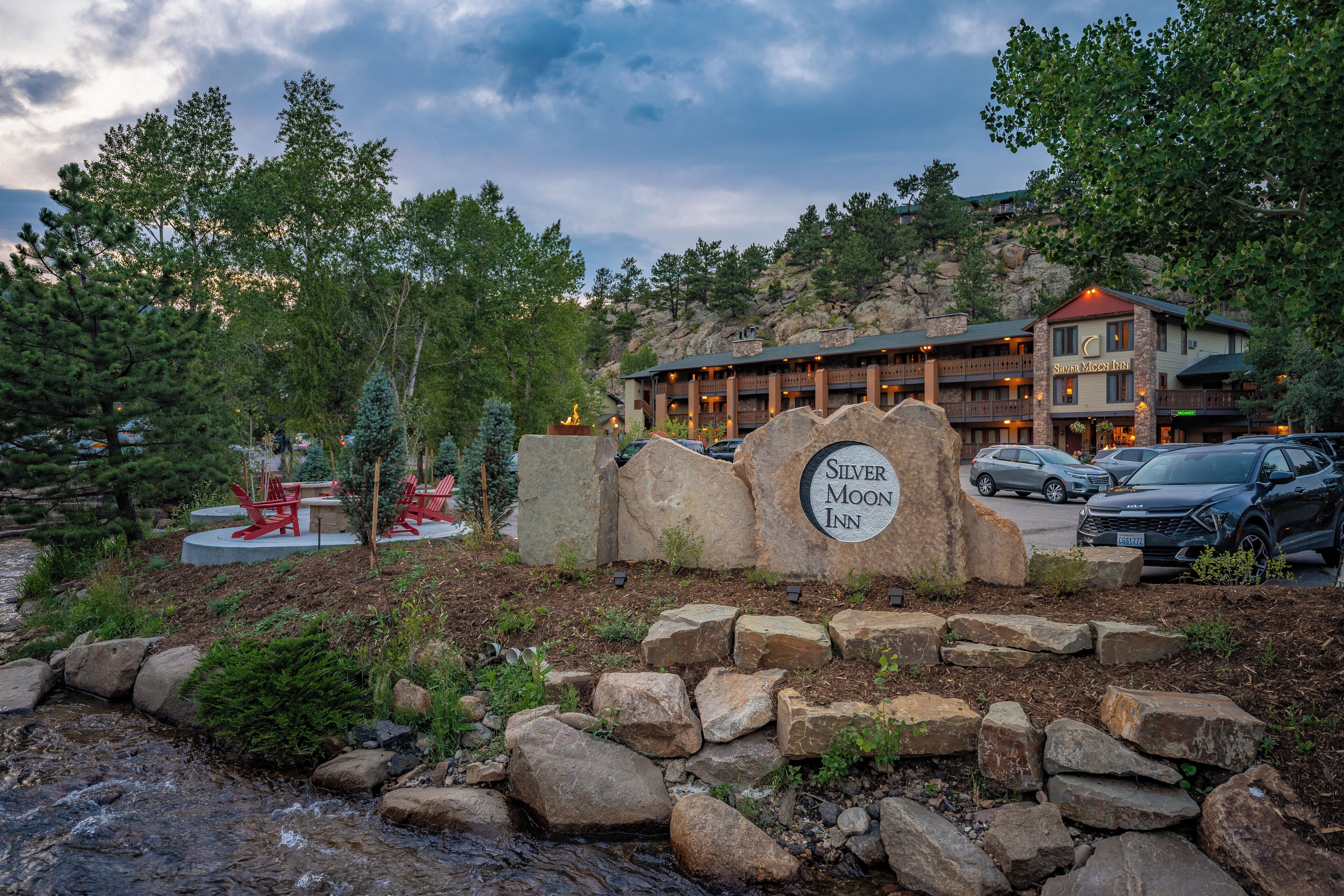 A hotel sign with a mountainous backdrop and a parking area in front.