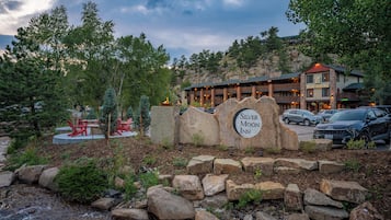 A hotel sign with a mountainous backdrop and a parking area in front.