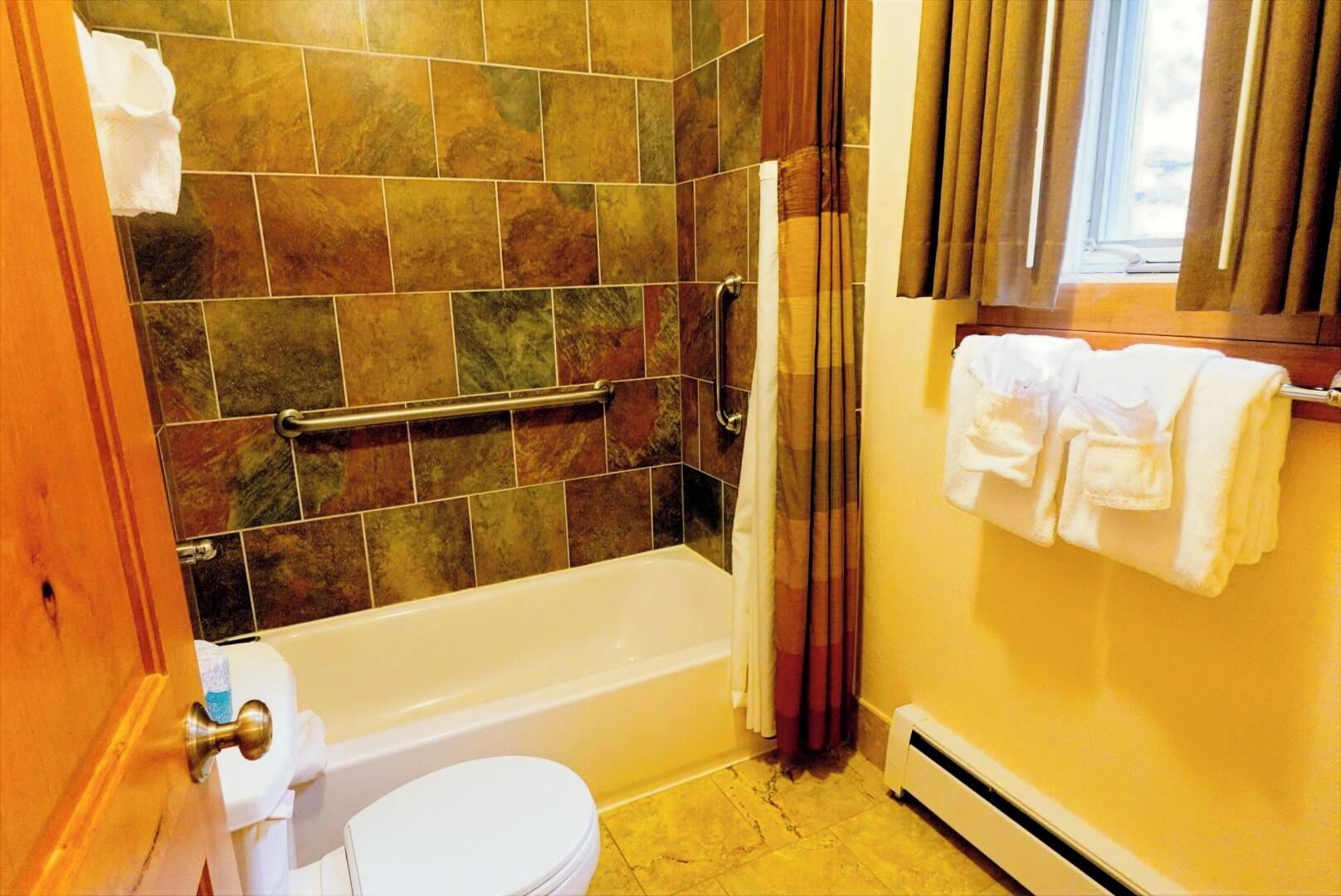 A bathroom with a bathtub, toilet, and a towel rack.