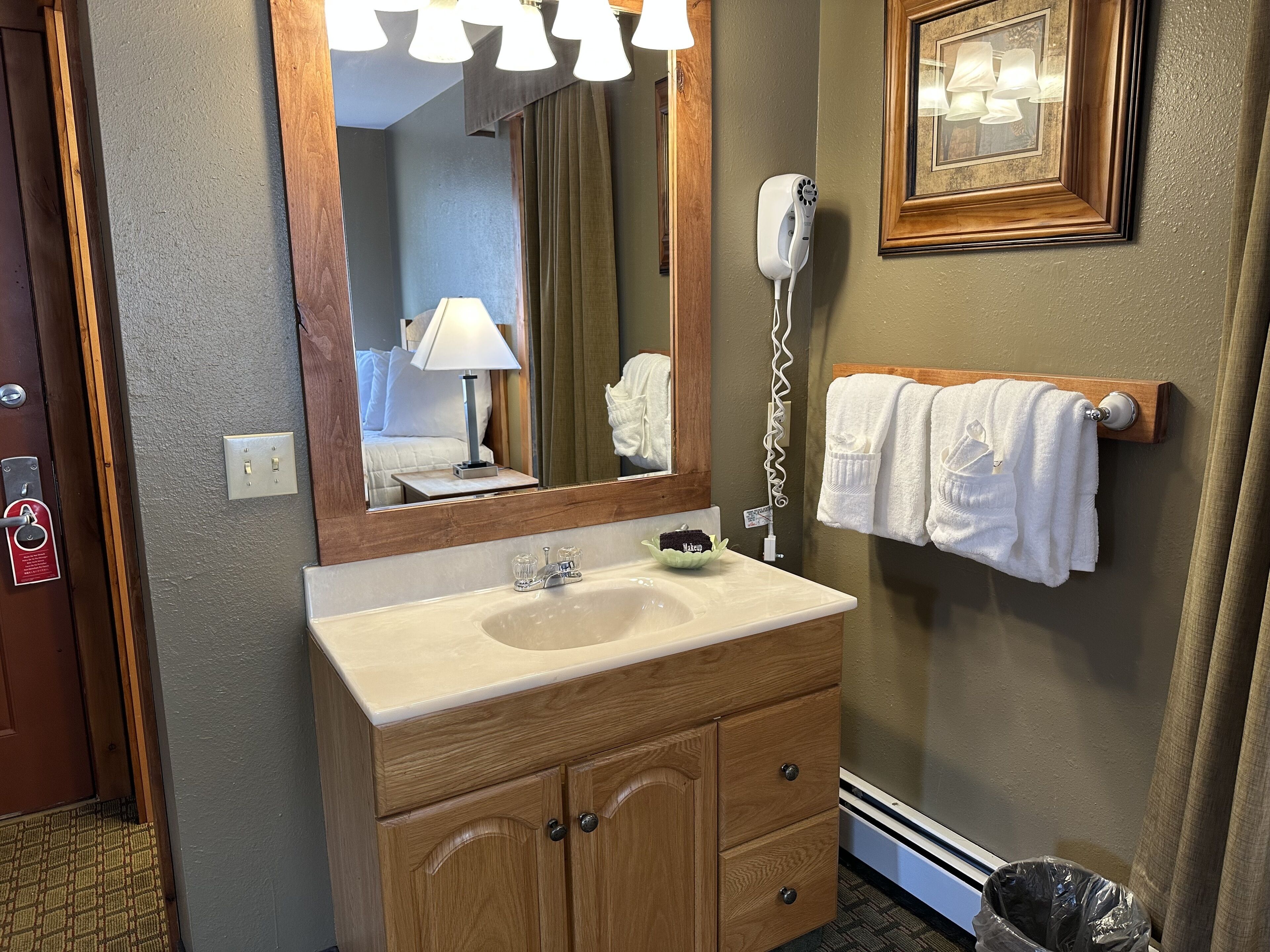 A bathroom with a wooden vanity, a mirror, a hairdryer, and a towel rack.