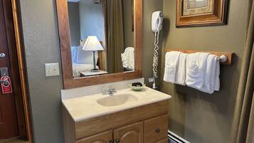 A bathroom with a wooden vanity, a mirror, a hairdryer, and a towel rack.