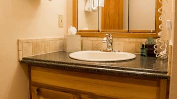 A bathroom with a wooden vanity, a sink, a mirror, and a hairdryer.