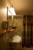 Baño con lavamanos, espejo, secador de pelo y cortina de ducha.