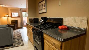 A kitchen with a stove, microwave, and oven. There is a chair and a couch in the adjacent living area.