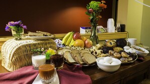 Um buffet de café da manhã com diversos alimentos, bebidas e um vaso de flores.