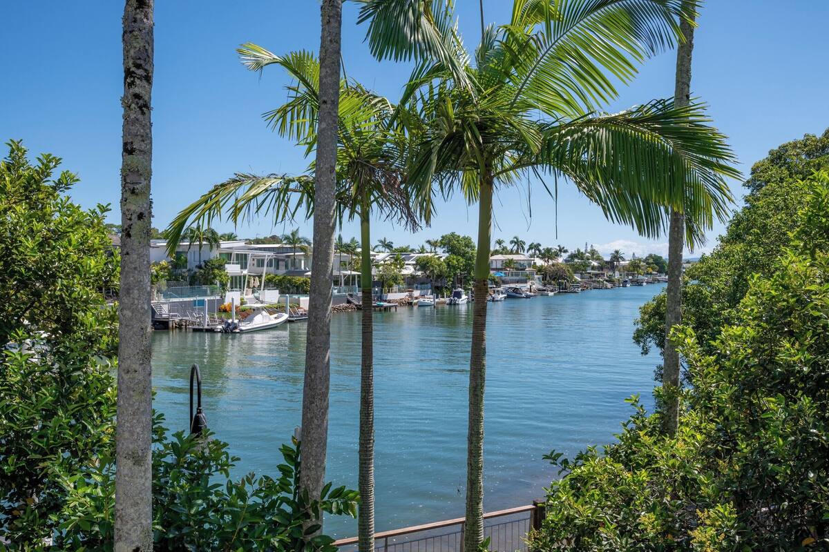 A marina with boats docked, surrounded by palm trees and a clear blue sky.