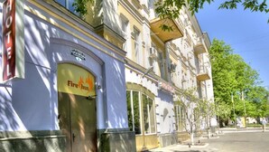 A hotel facade with a 'Fire Inn' sign, a visible entrance, and a street view with trees and a clear sky. - Fire Inn (Kyiv)