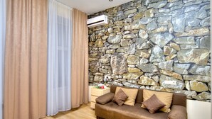 A room with a stone wall, a brown sofa with cushions, and a wooden floor. - Fire Inn (Kyiv)