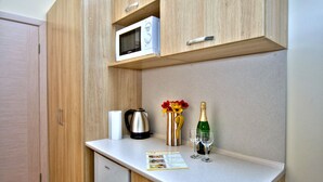 A compact kitchenette with a microwave, a coffee maker, a small refrigerator, and a countertop with a menu. - Fire Inn (Kyiv)