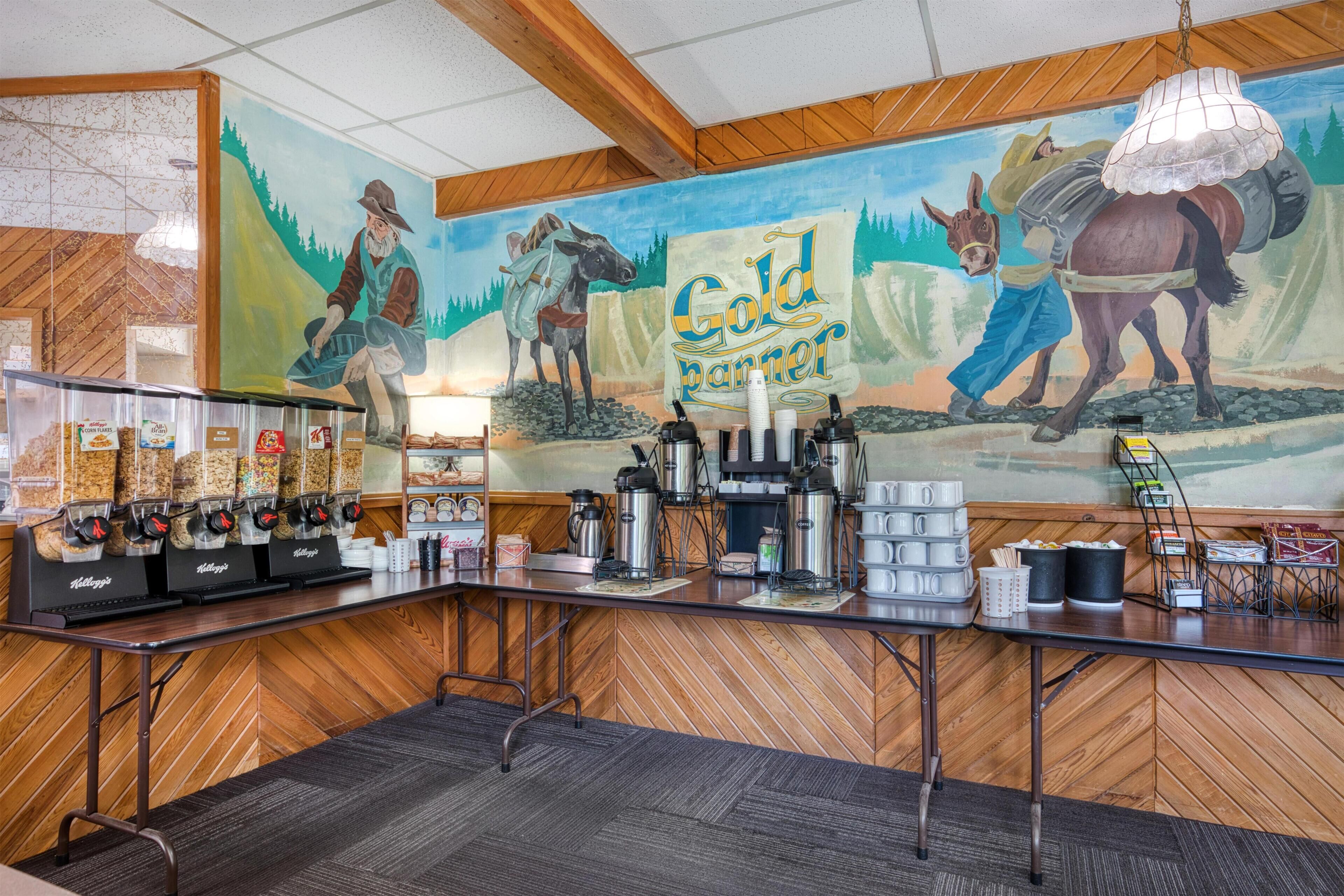 A coffee station with a mural of a cowboy and a horse, wooden paneling, and a coffee machine.