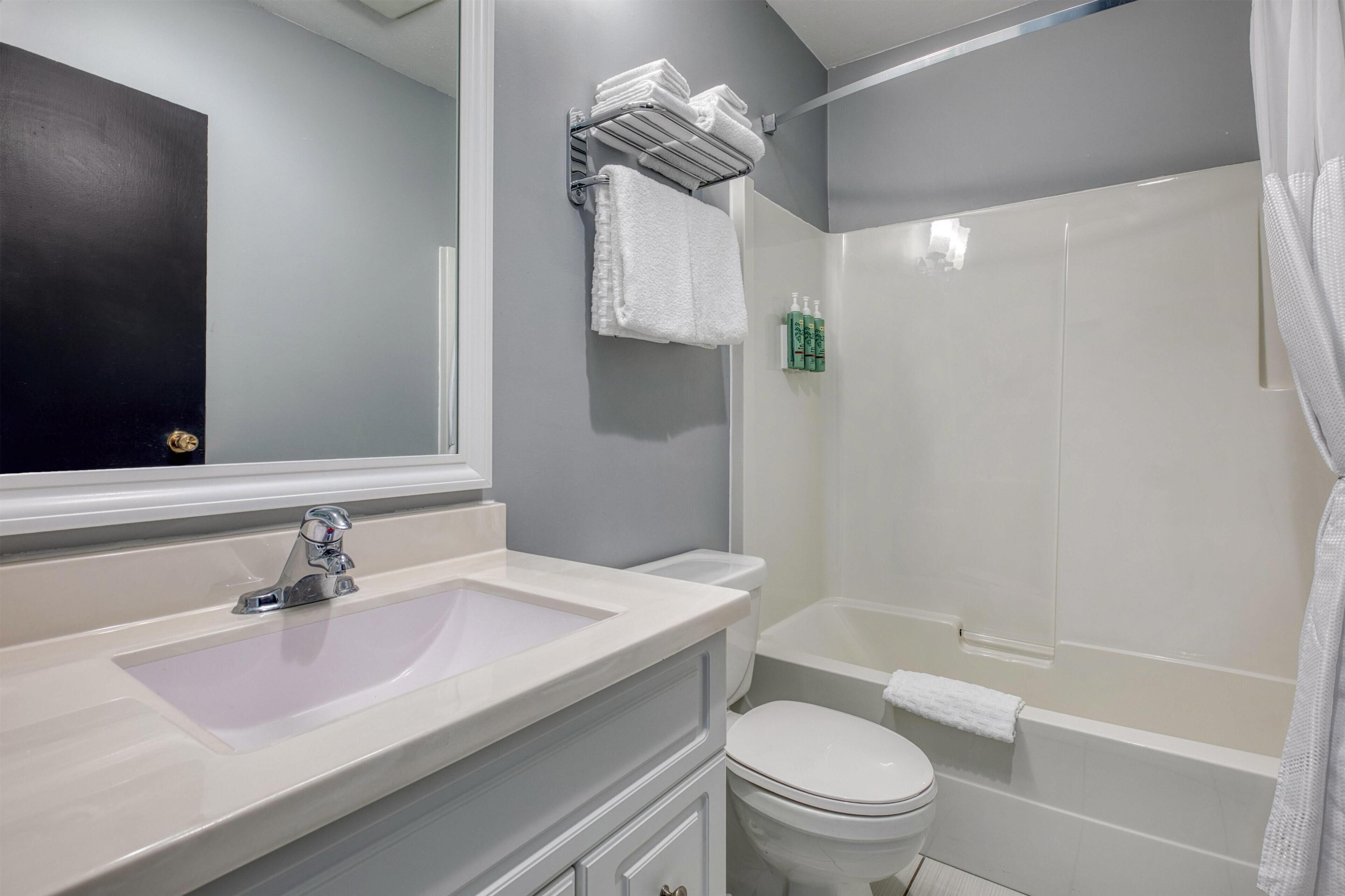 A bathroom with a sink, toilet, and shower area.
