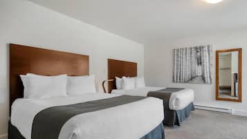 A hotel room with two beds, a large mirror, and a wall-mounted artwork.