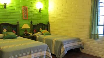 Quarto com duas camas, paredes verdes, teto de tijolos e uma janela com cortinas.
