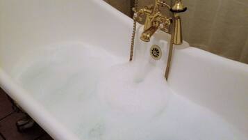 A bathtub with a gold faucet and a drain.