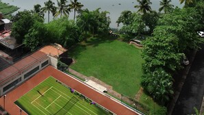 A tennis court with a view of a river and a bridge. - Riviera Suites (Kanayannur)
