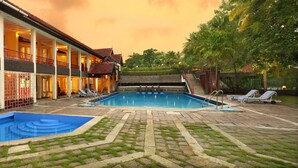A two-story building with a swimming pool, a covered patio, and a landscaped garden. - Riviera Suites (Kanayannur)
