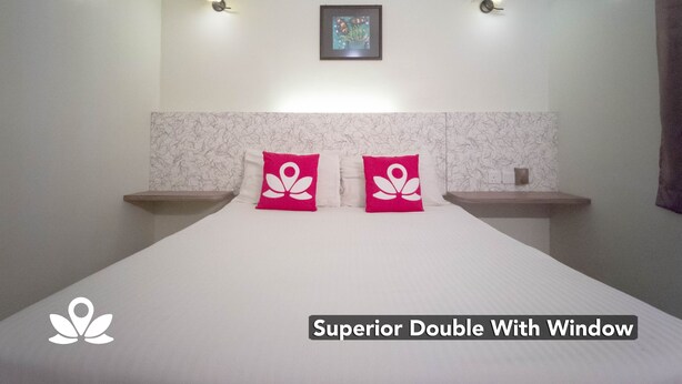 Habitación doble superior con ventana, con una cama y dos almohadas, un cuadro enmarcado en la pared y dos luces fijadas a la pared.