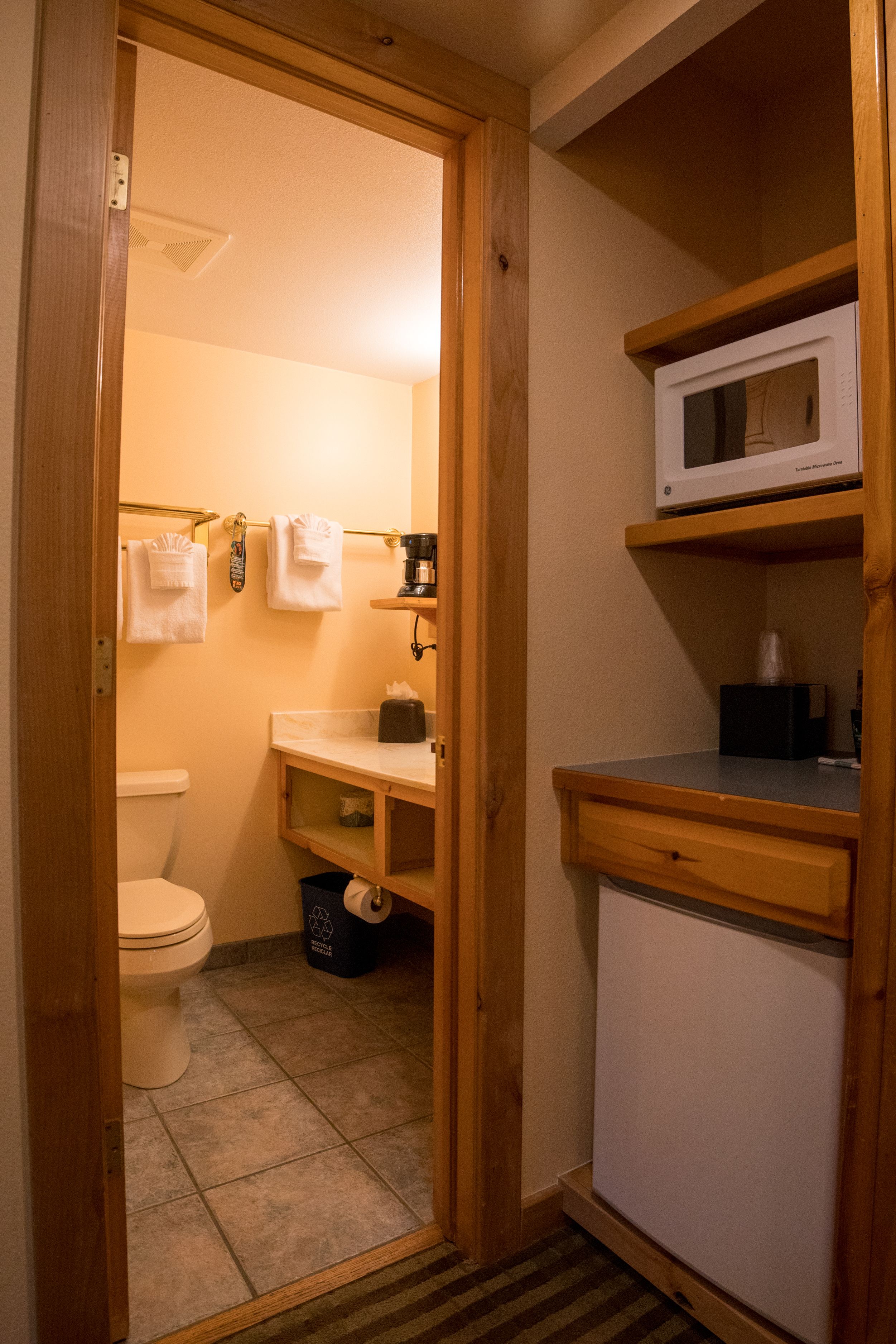 Ein kleines Badezimmer mit Toilette, Waschbecken, Mikrowelle und einem kleinen Schrank.