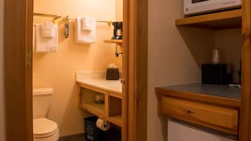 Ein kleines Badezimmer mit Toilette, Waschbecken, Mikrowelle und einem kleinen Schrank.