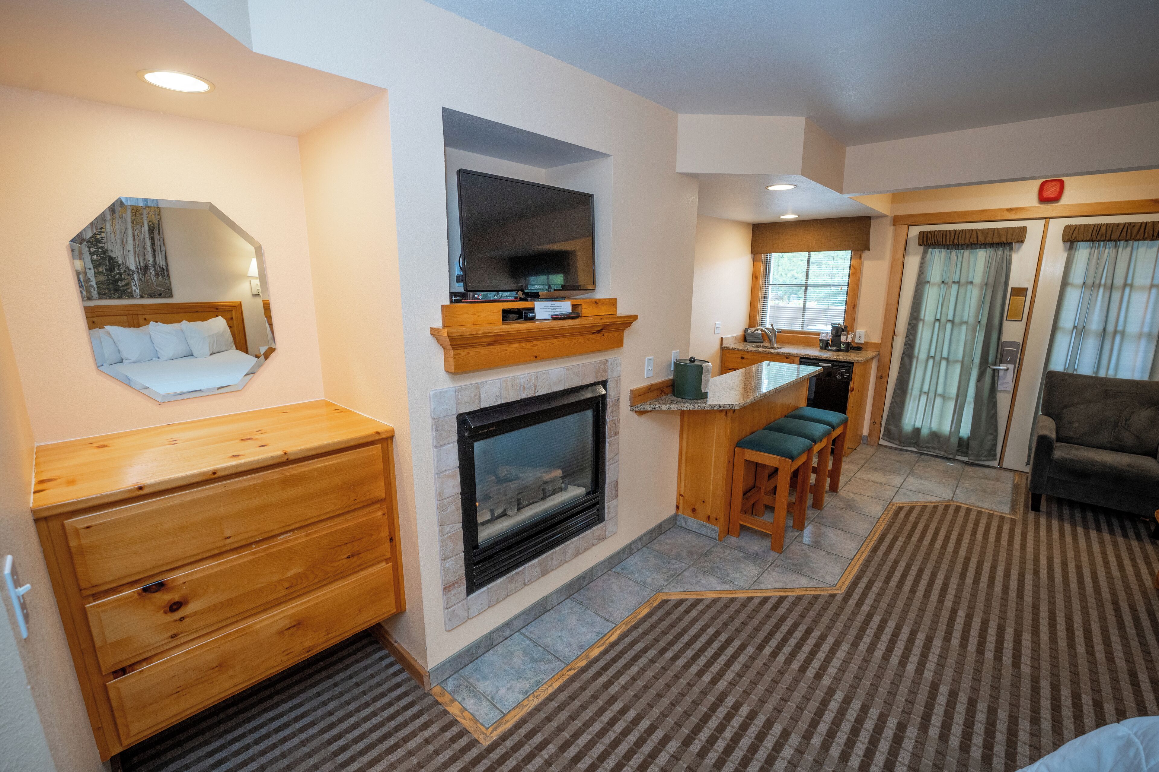 Une chambre d’hôtel avec une cheminée, des meubles en bois, un miroir et une vue sur l’extérieur.