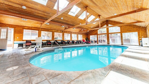 An indoor swimming pool with a wooden ceiling and large windows.