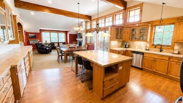 Una cocina amplia con armarios de madera, una isla central y una zona de comedor con sillas.