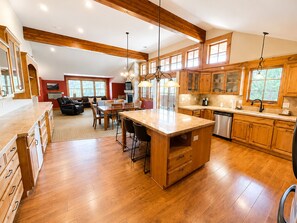A spacious kitchen with wooden cabinets, a central island, and a dining area with chairs. - Appenzell Inn (Estes Park)