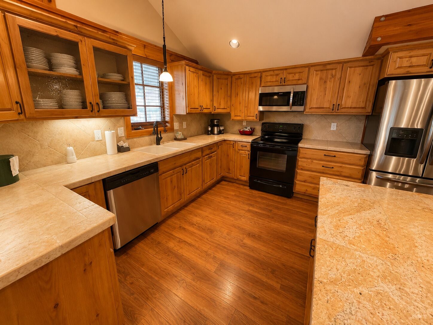 A kitchen with wooden cabinets, stainless steel appliances, a dishwasher, and a granite countertop.