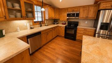 A kitchen with wooden cabinets, stainless steel appliances, a dishwasher, and a granite countertop.