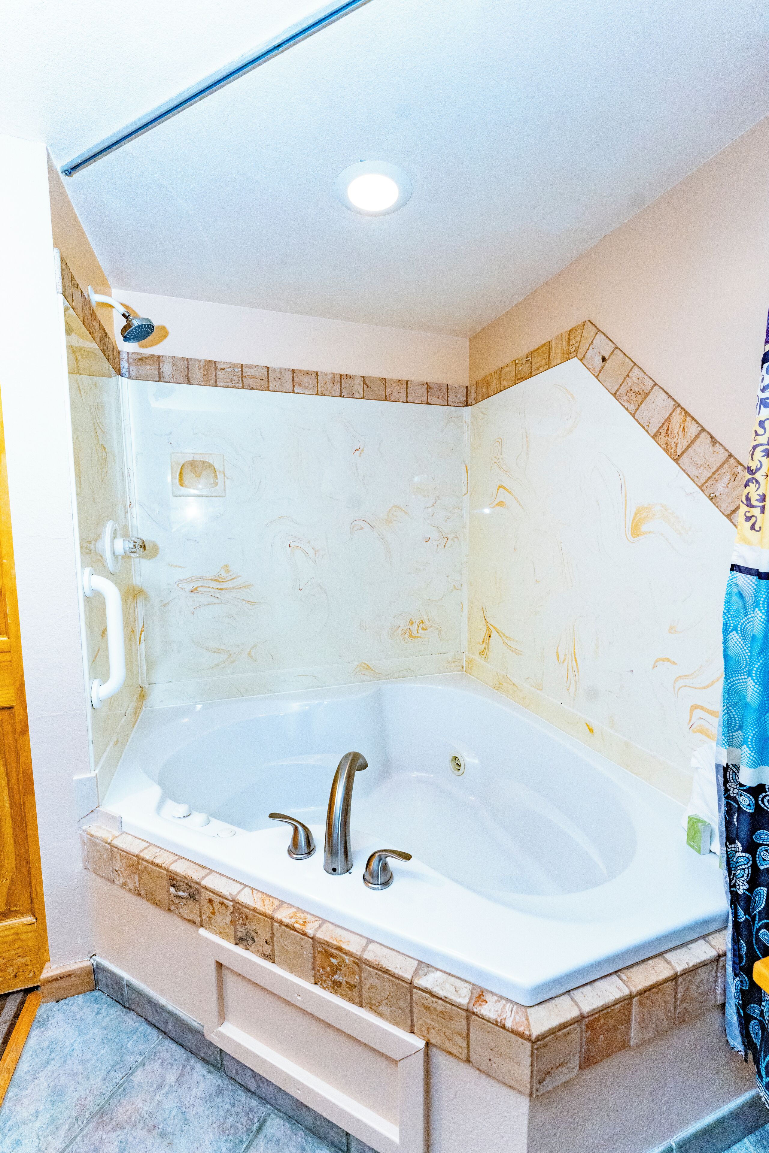 A large freestanding bathtub with a marble surround, a built-in showerhead, and a shower curtain.