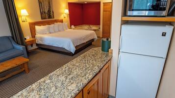 A compact hotel room with a bed, a small kitchenette, a microwave, and a refrigerator.