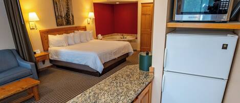 Une chambre d’hôtel de taille réduite, équipée d’un lit, d’une petite kitchenette, d’un four à micro-ondes et d’un réfrigérateur.