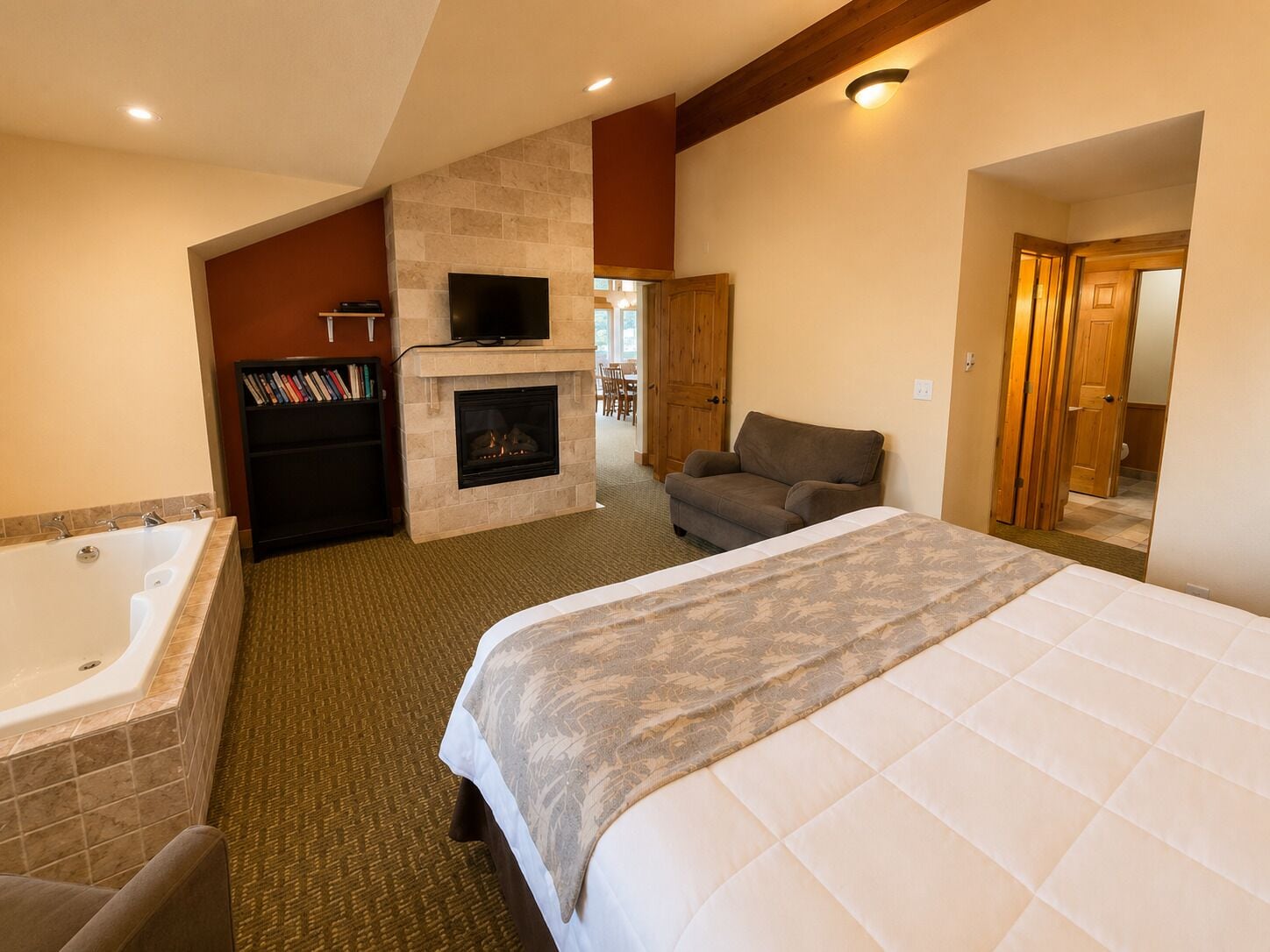 A hotel room with a large bed, a fireplace, a television, and a bathtub.