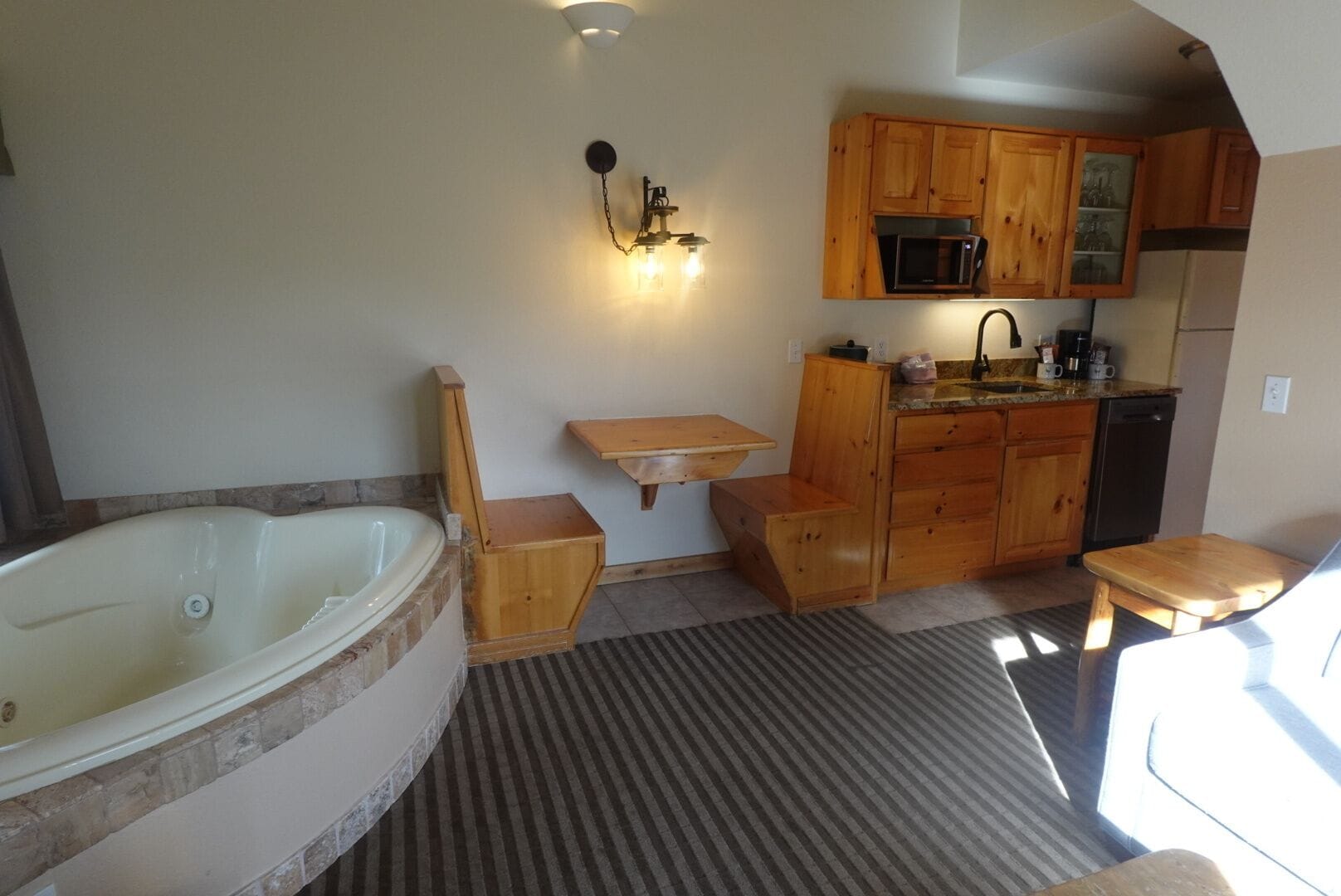 A compact bathroom with a bathtub, wooden cabinets, a microwave, and a sink.