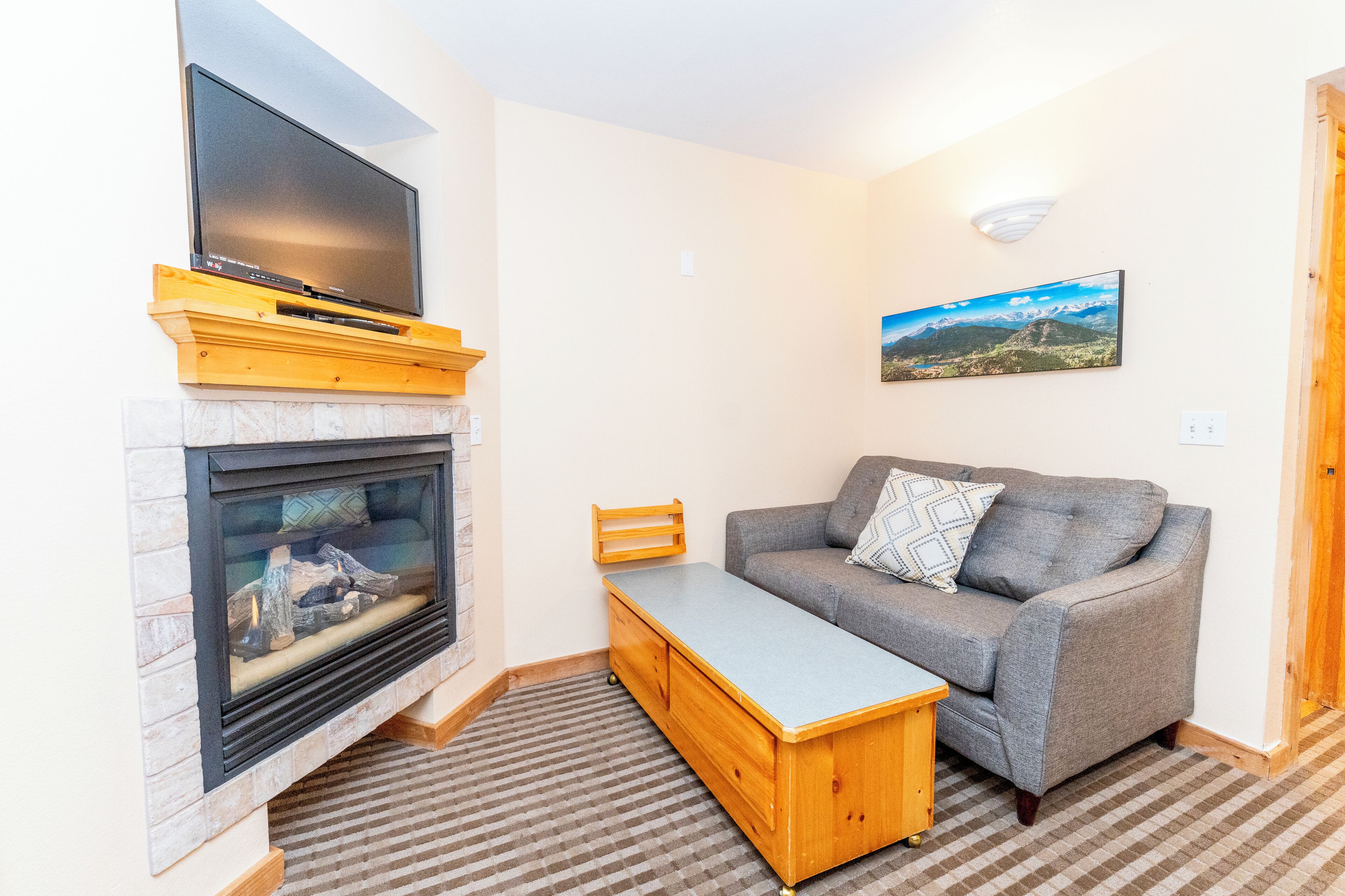 A living room with a fireplace, a flat-screen TV, a grey sofa, and a wooden coffee table.