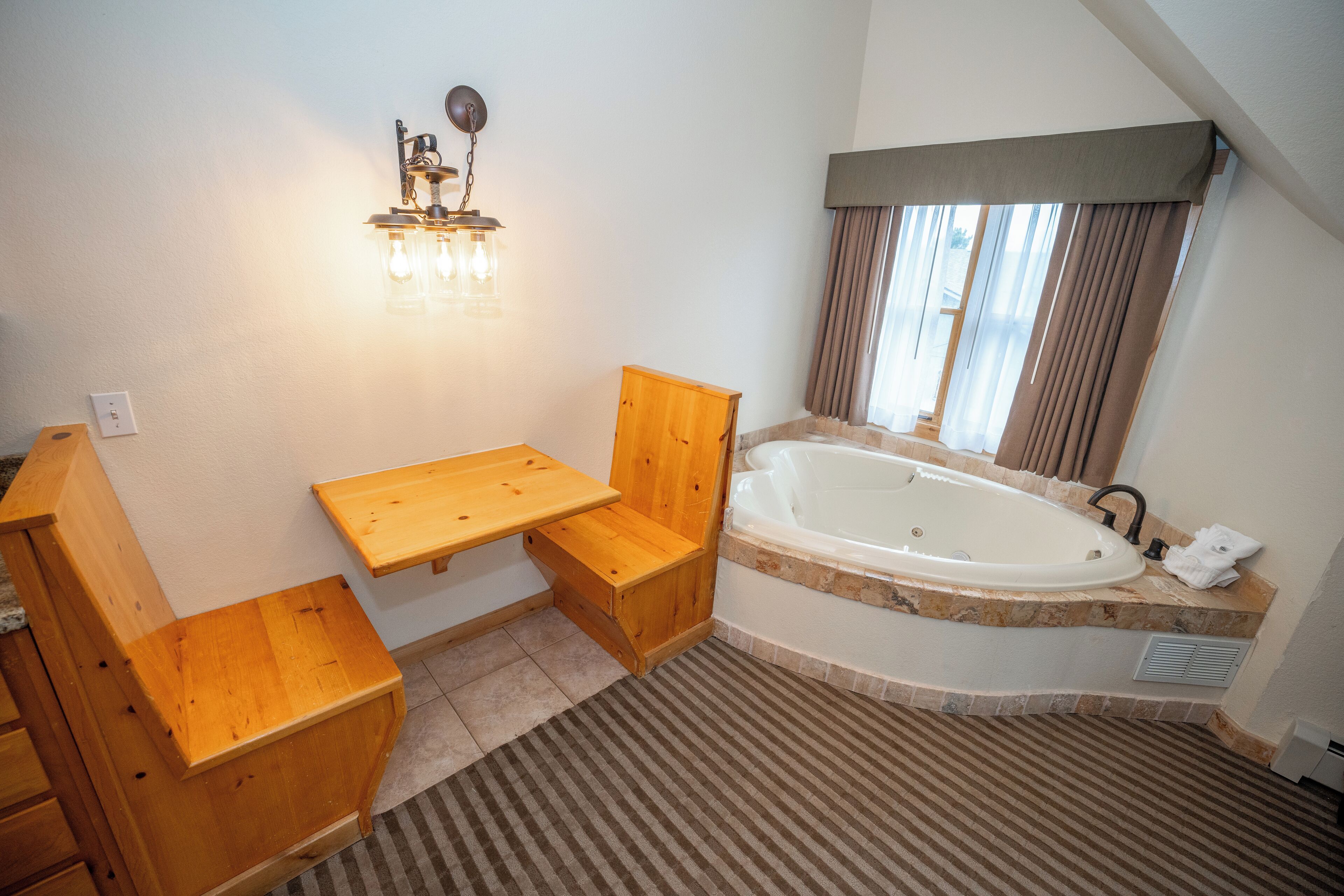 A bathroom with a wooden vanity, a bathtub, and a light fixture.