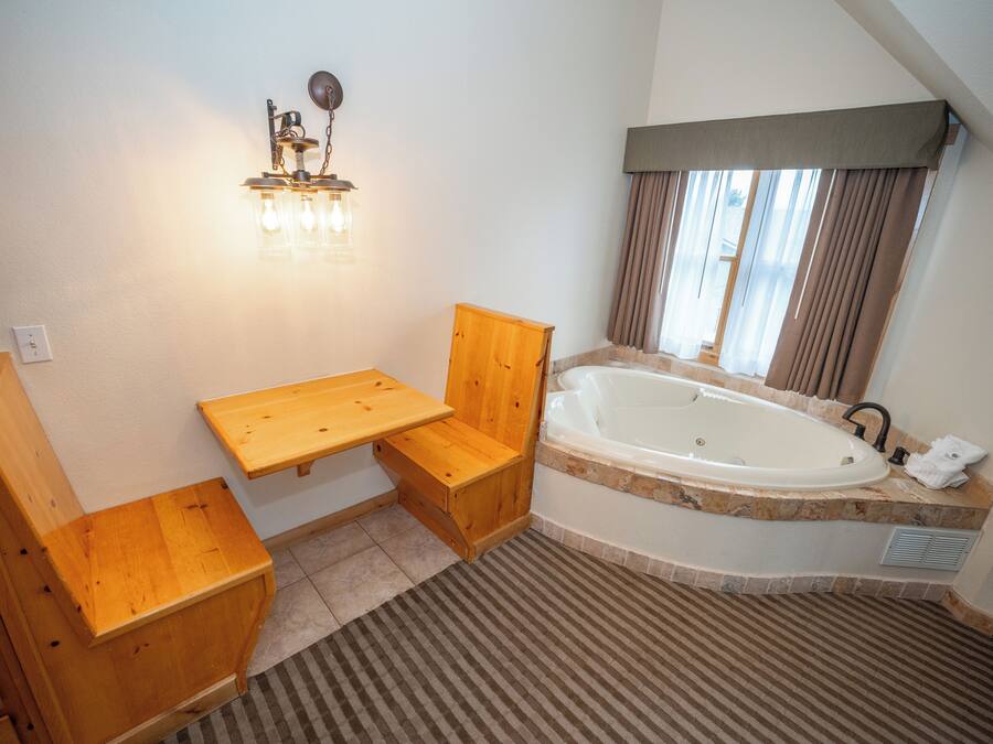 A bathroom with a wooden vanity, a bathtub, and a light fixture.