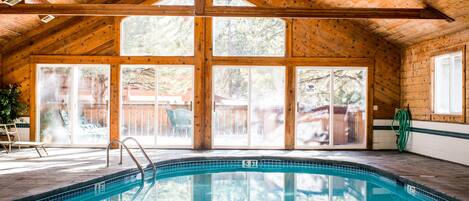 An indoor swimming pool with wooden beams and large windows.