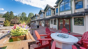A patio with red Adirondack chairs, a round table, and a flower planter.