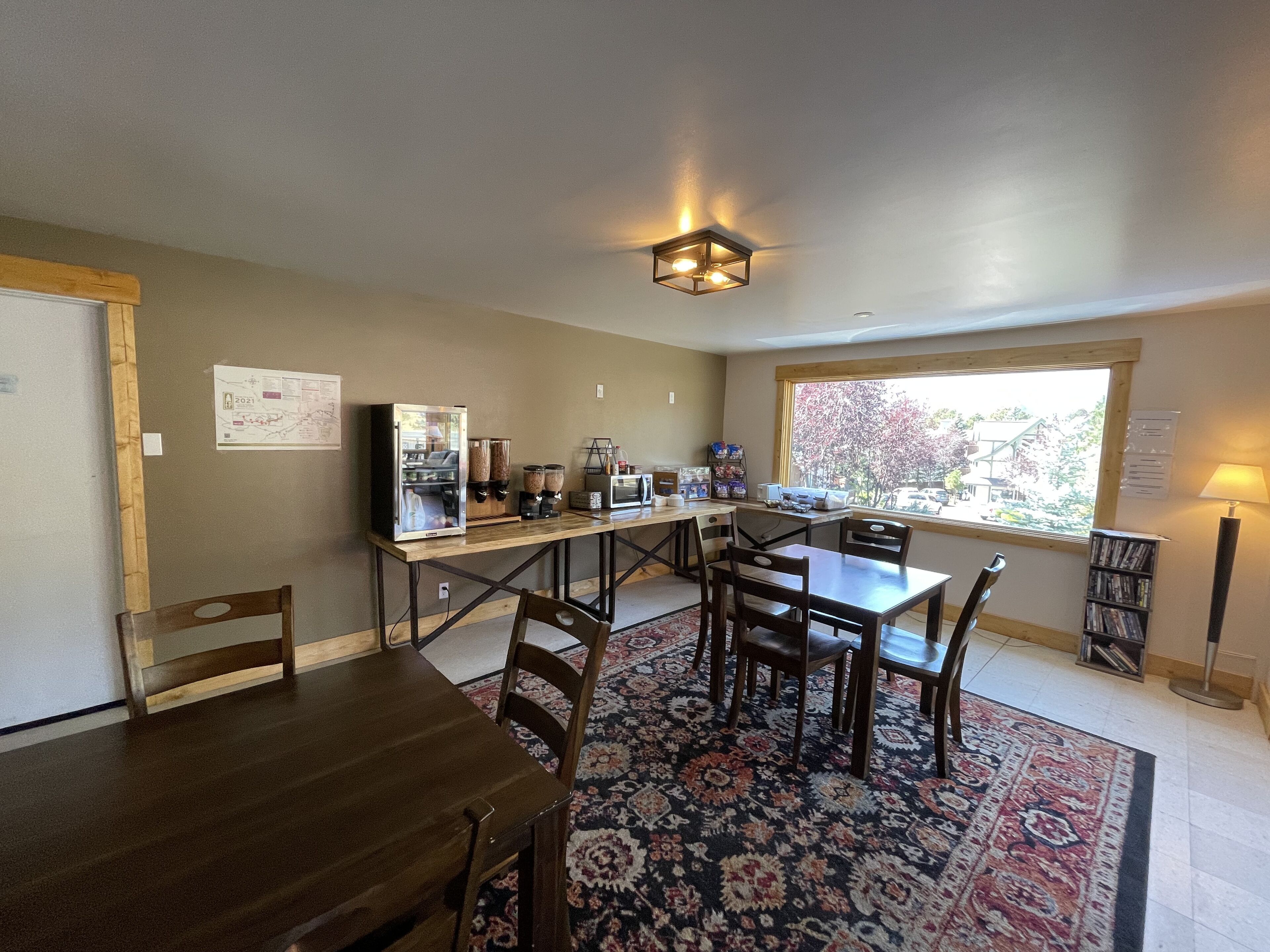A cozy dining area with a wooden table and chairs, a coffee machine, and a refrigerator.