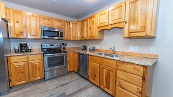 A kitchen with wooden cabinets, stainless steel appliances, and a granite countertop.