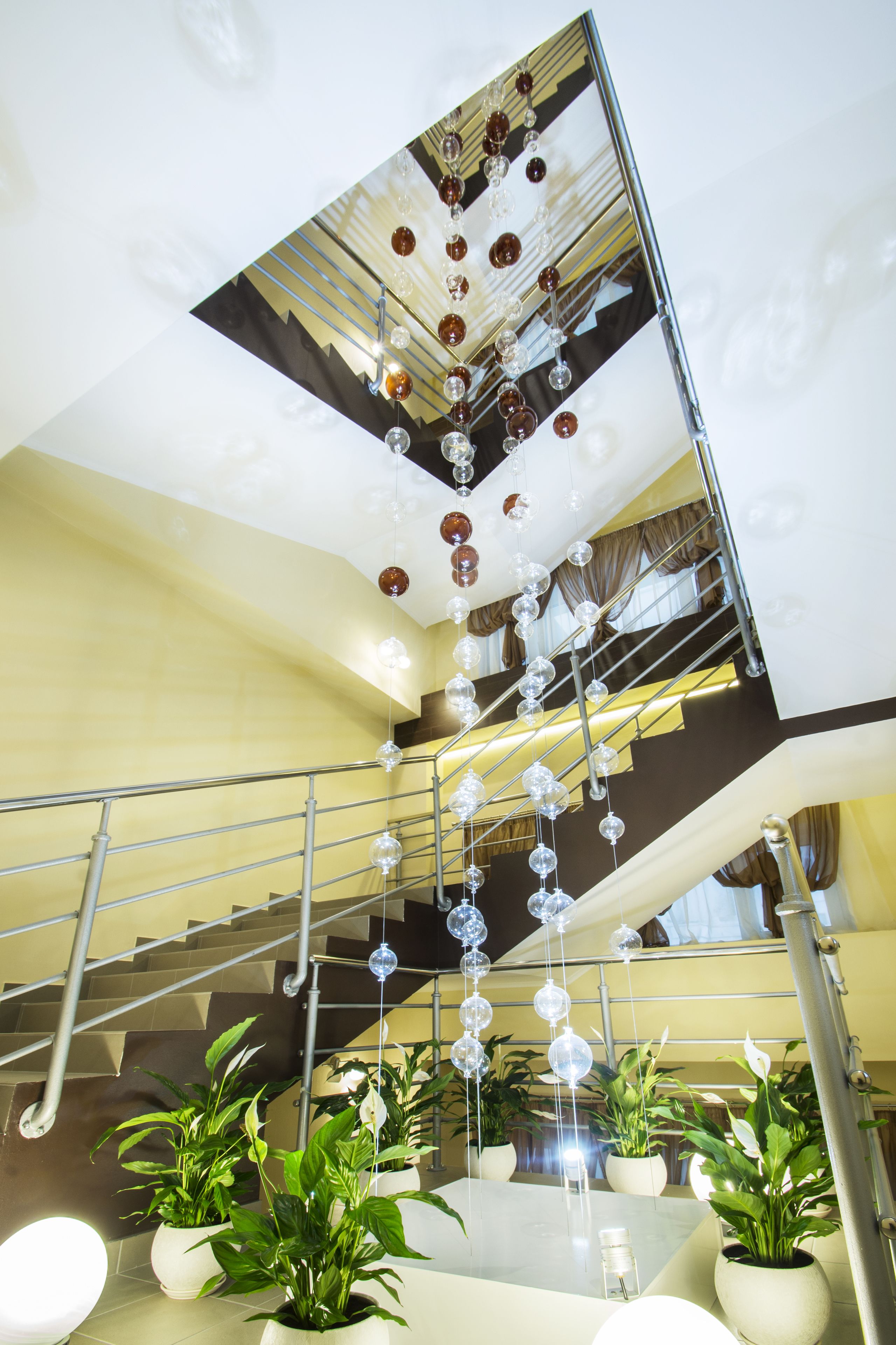 Un intérieur à plusieurs niveaux, agrémenté d’un escalier, de plantes en pot et d’éléments décoratifs suspendus.