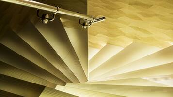 A staircase with a textured wall and a metal handrail.