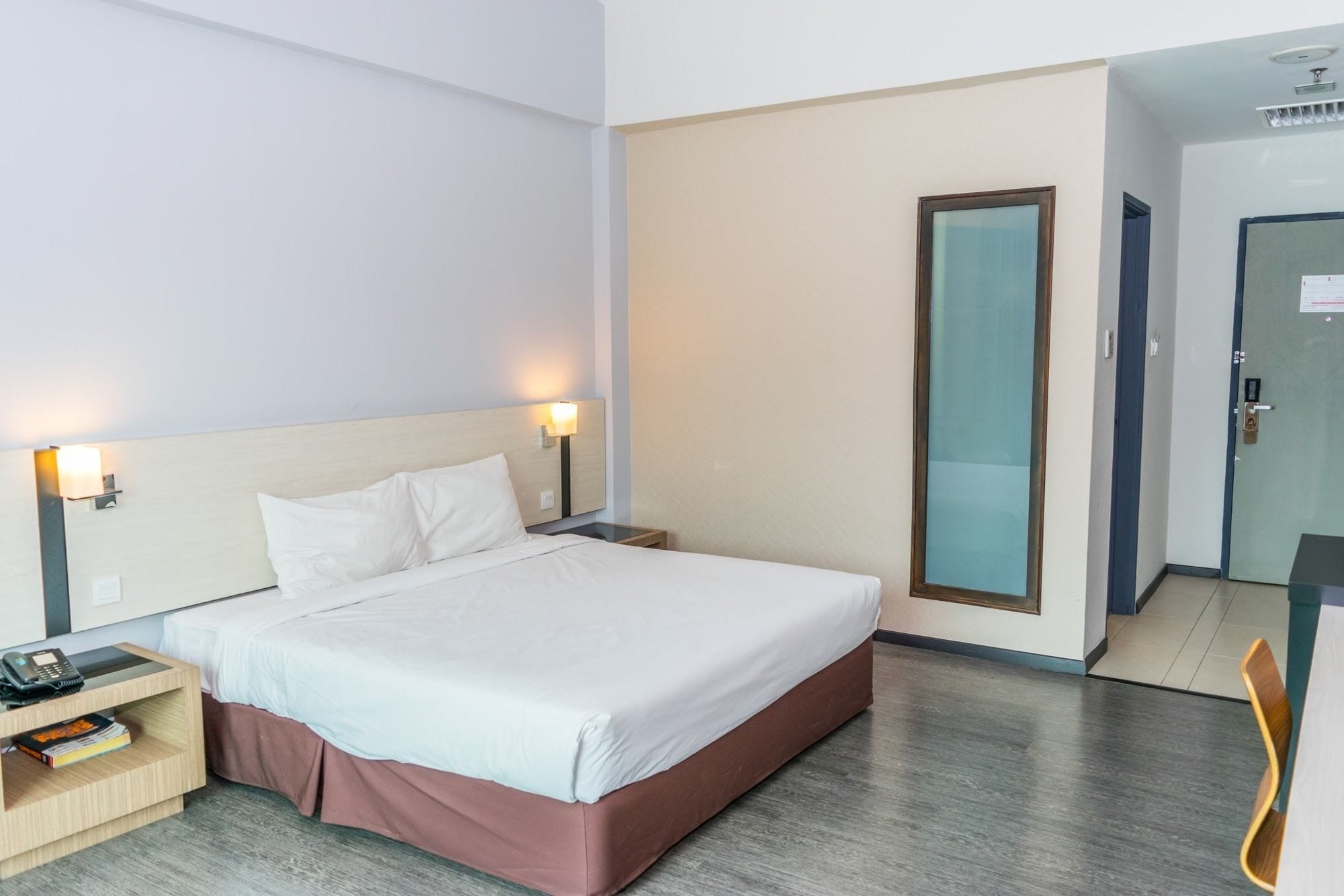 A hotel room with a bed, bedside tables, a desk, and a chair.