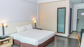 A hotel room with a bed, bedside tables, a desk, and a chair.