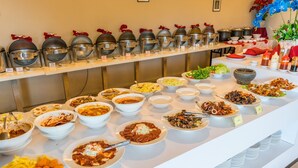Un buffet proposant divers plats et une rangée de récipients couverts contenant de la nourriture.