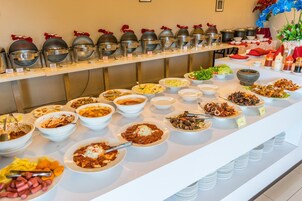 A buffet with various dishes and a row of covered food containers.